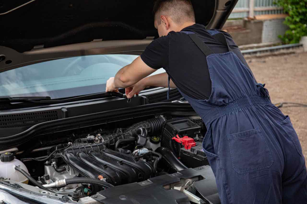 Mechanic working on a car engine with the hood open